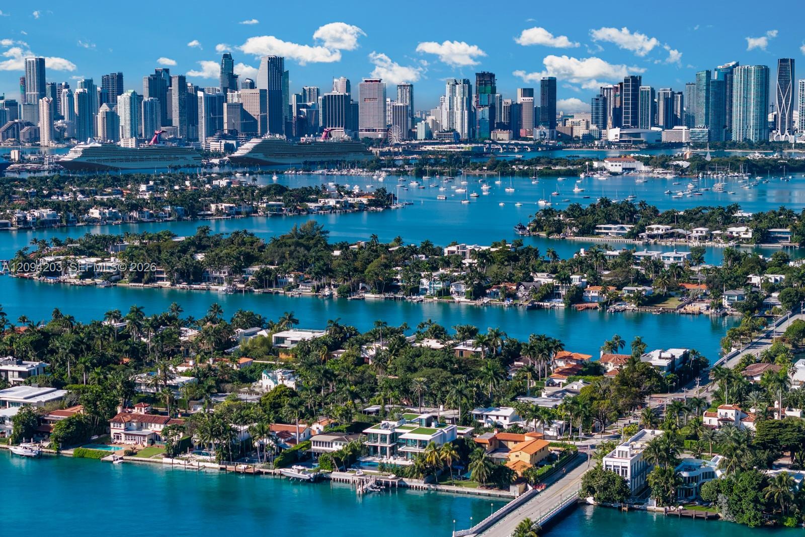 Aerial view of Miami Beach waterways and homes with the downtown Miami skyline in the distance.