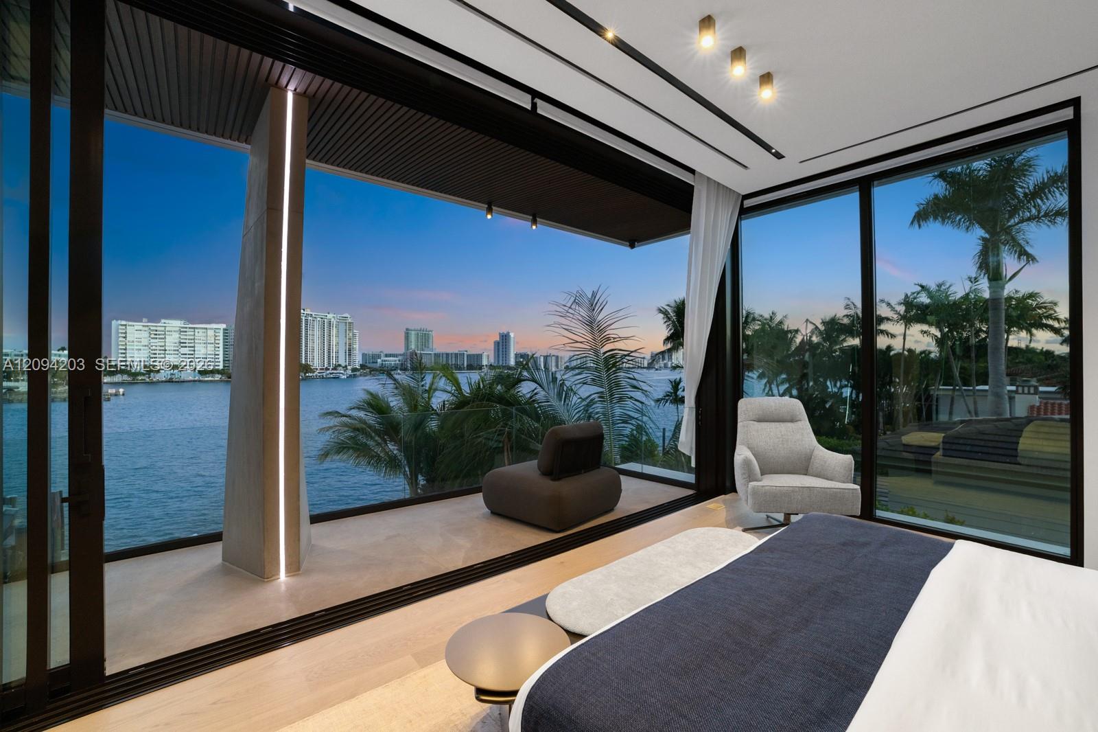 Modern bedroom with floor-to-ceiling windows overlooking the bay and a covered terrace.