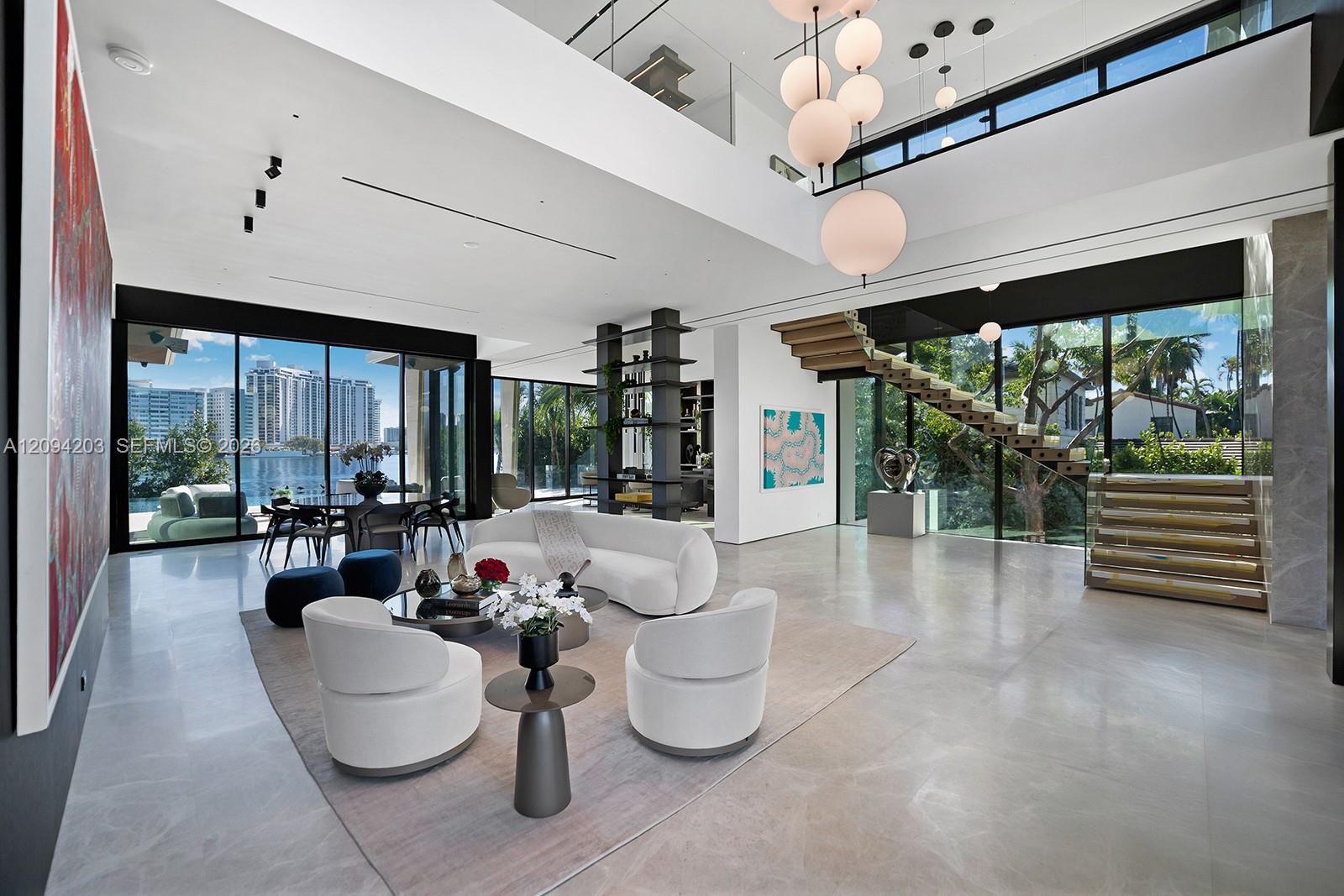 Modern living room with sculptural white seating, a floating staircase, and waterfront views.