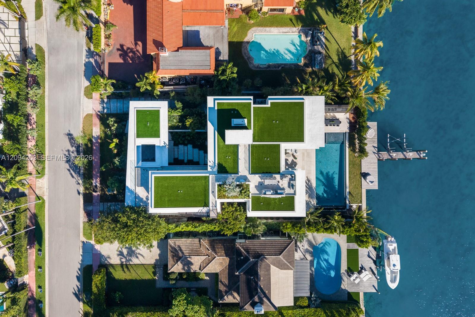 Modern waterfront home with geometric green roofs, a swimming pool, and a dock viewed from above.