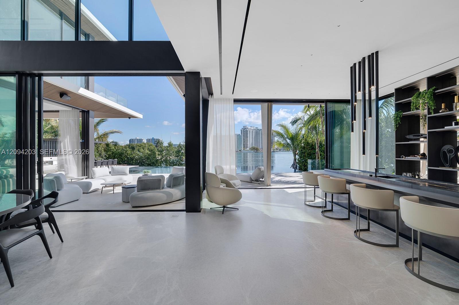 Modern open-plan living and dining area with floor-to-ceiling windows overlooking the water.