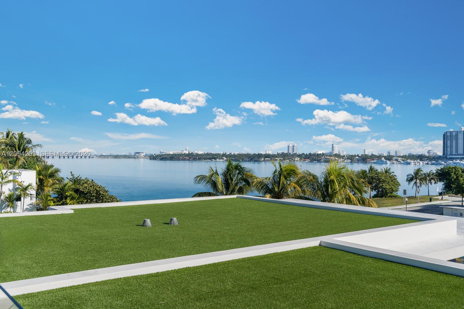 Rooftop lawn terrace overlooking the bay, palm trees, and Miami Beach skyline.