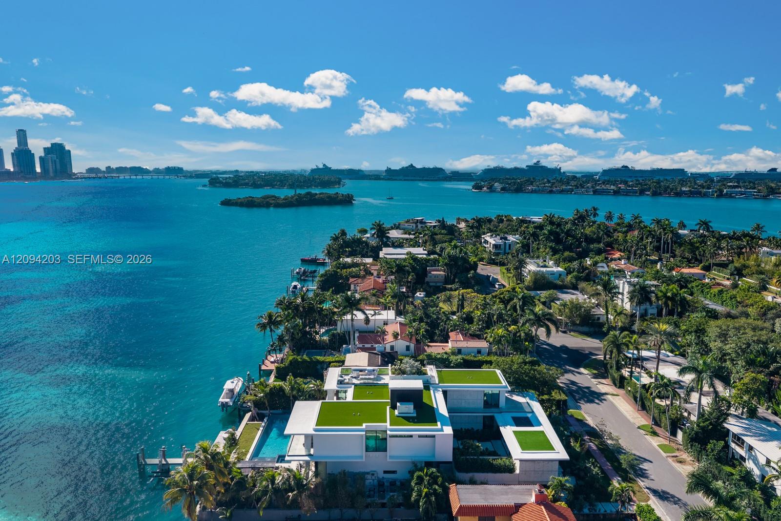 Modern waterfront home with a pool and docks, overlooking Biscayne Bay toward the Miami skyline.