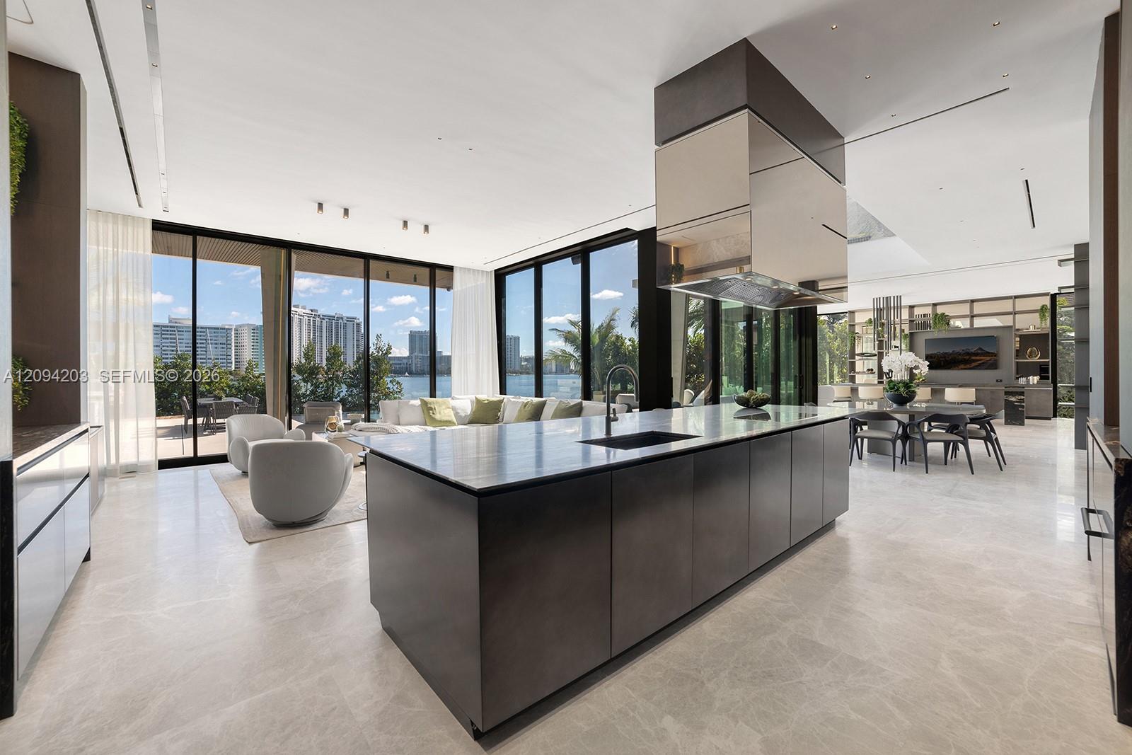Modern kitchen with a large dark island and floor-to-ceiling windows overlooking the water.