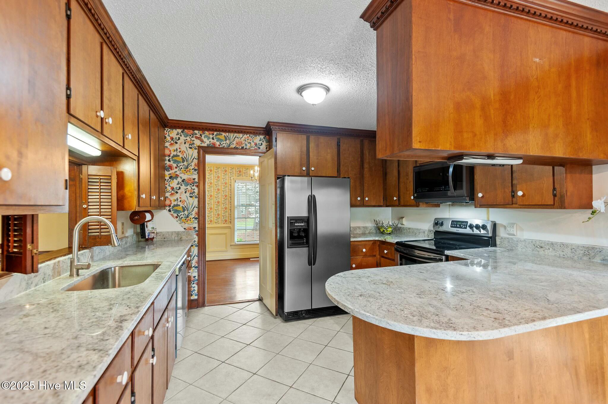 Kitchen with wood cabinets, granite counters, a curved breakfast bar, and stainless steel appliances.