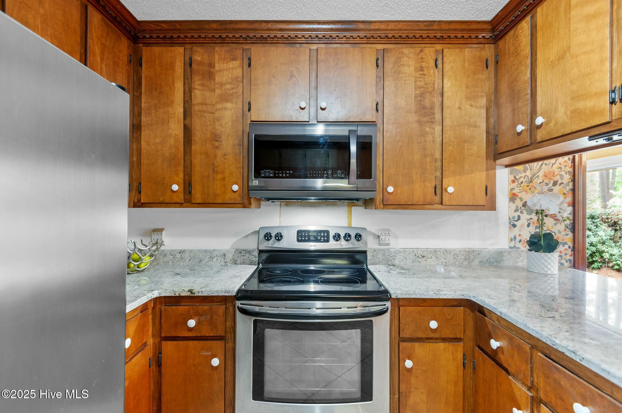 Kitchen with wood cabinets, stone counters, and stainless steel appliances.