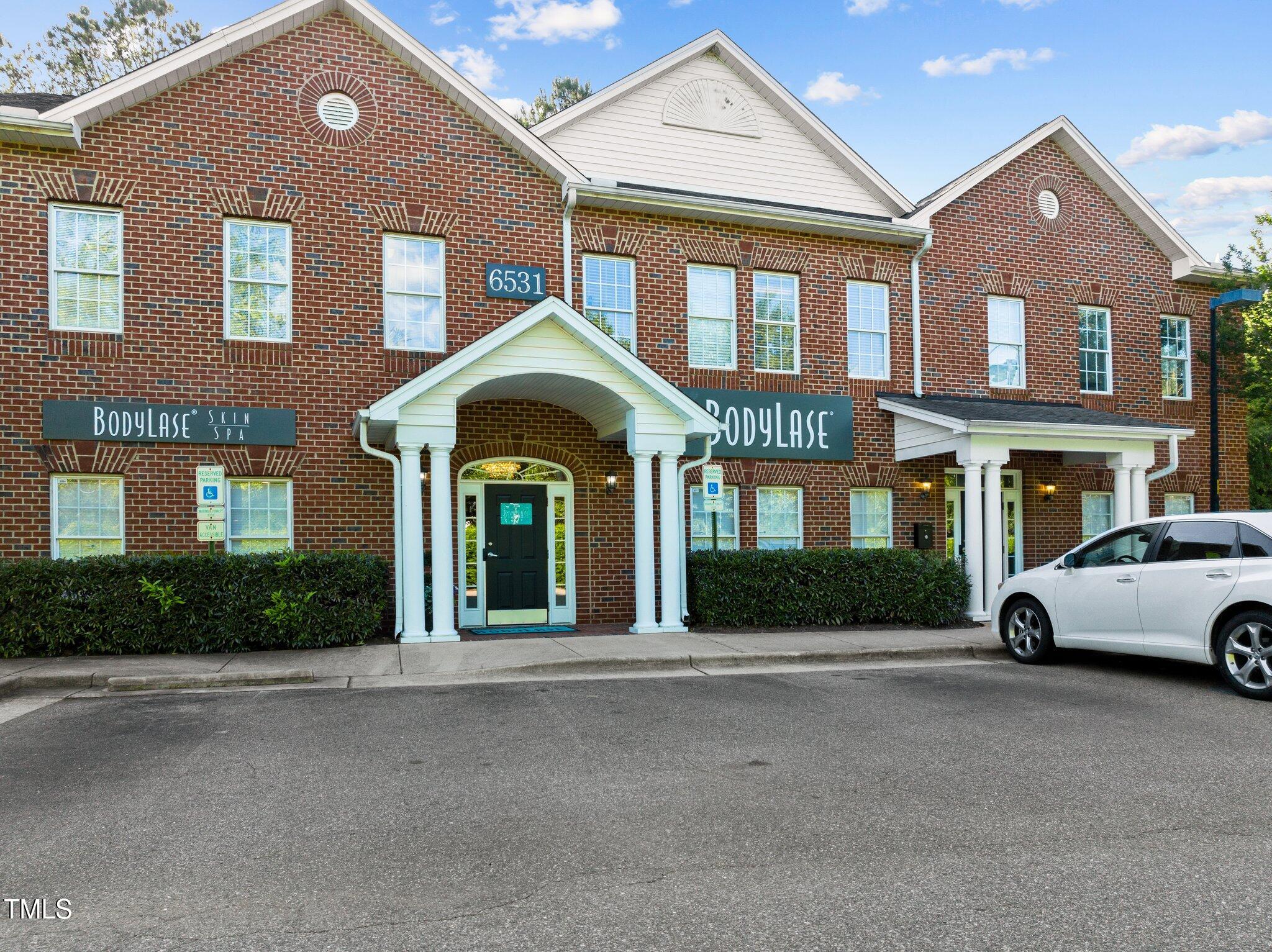 Two-story brick commercial building with white gabled entrances and BodyLase Skin Spa signs.