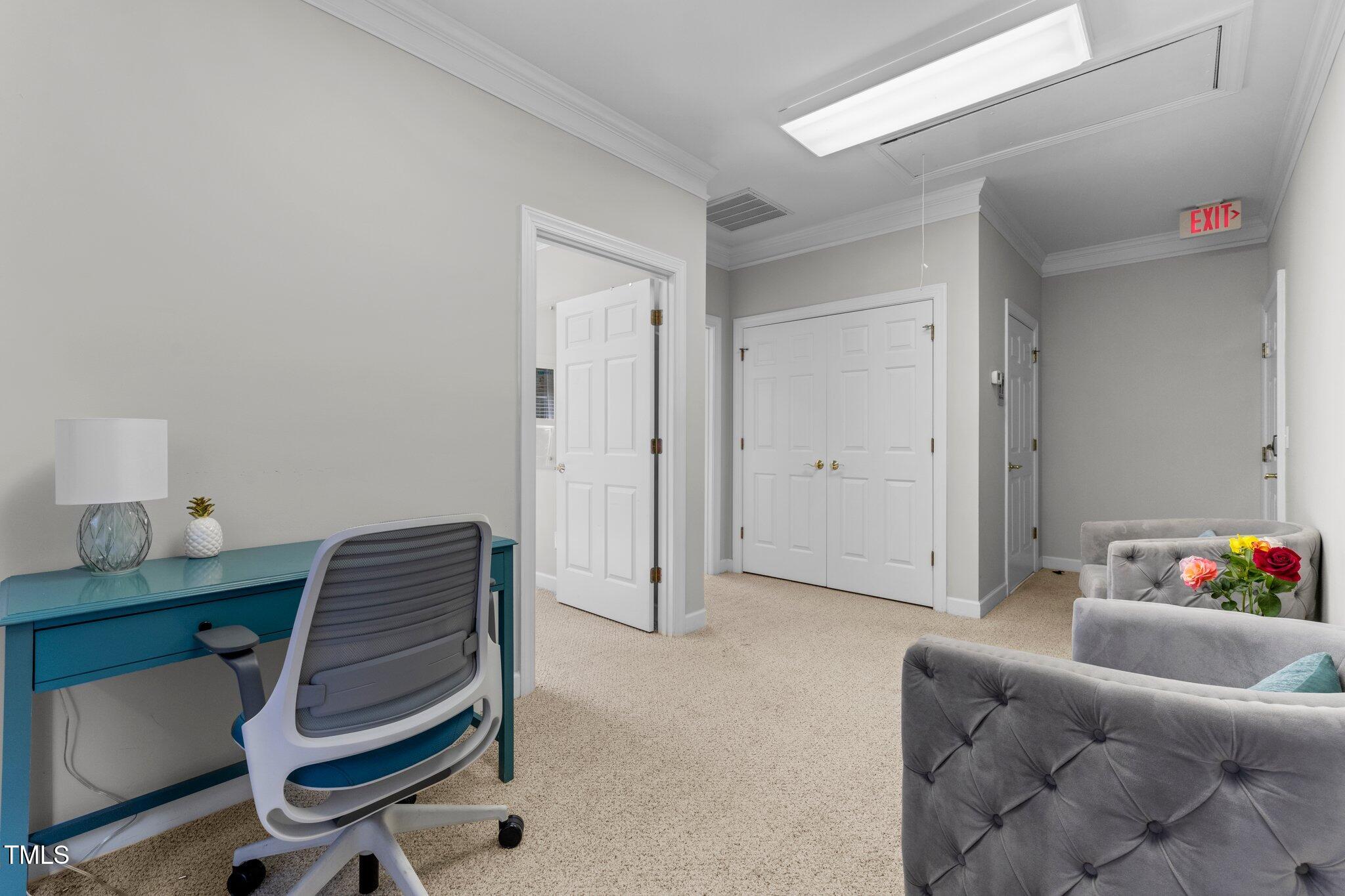 Staged office with a teal desk, gray seating, and white paneled doors.