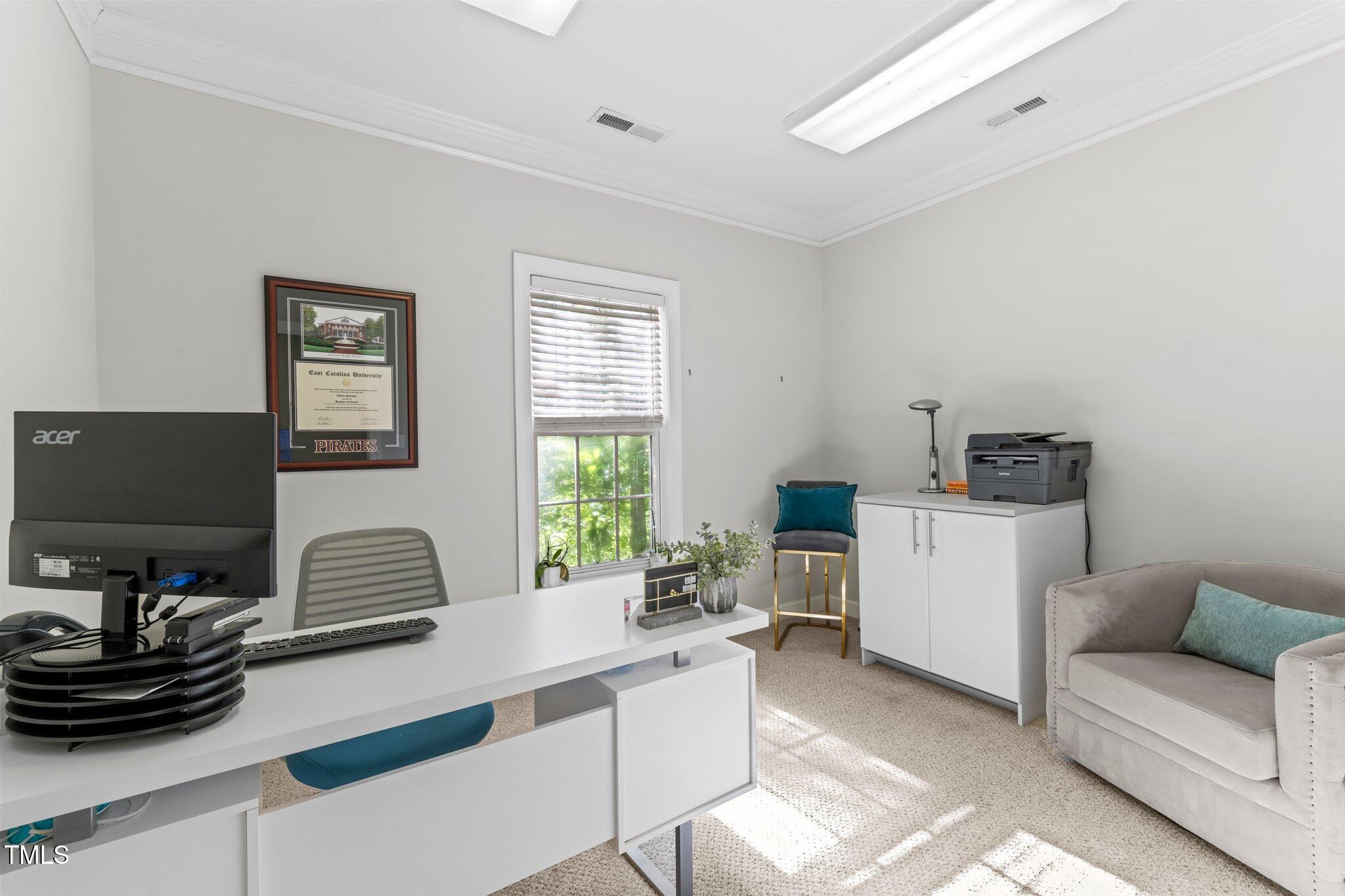 Furnished home office with a white desk, window, printer cabinet, and upholstered armchair.