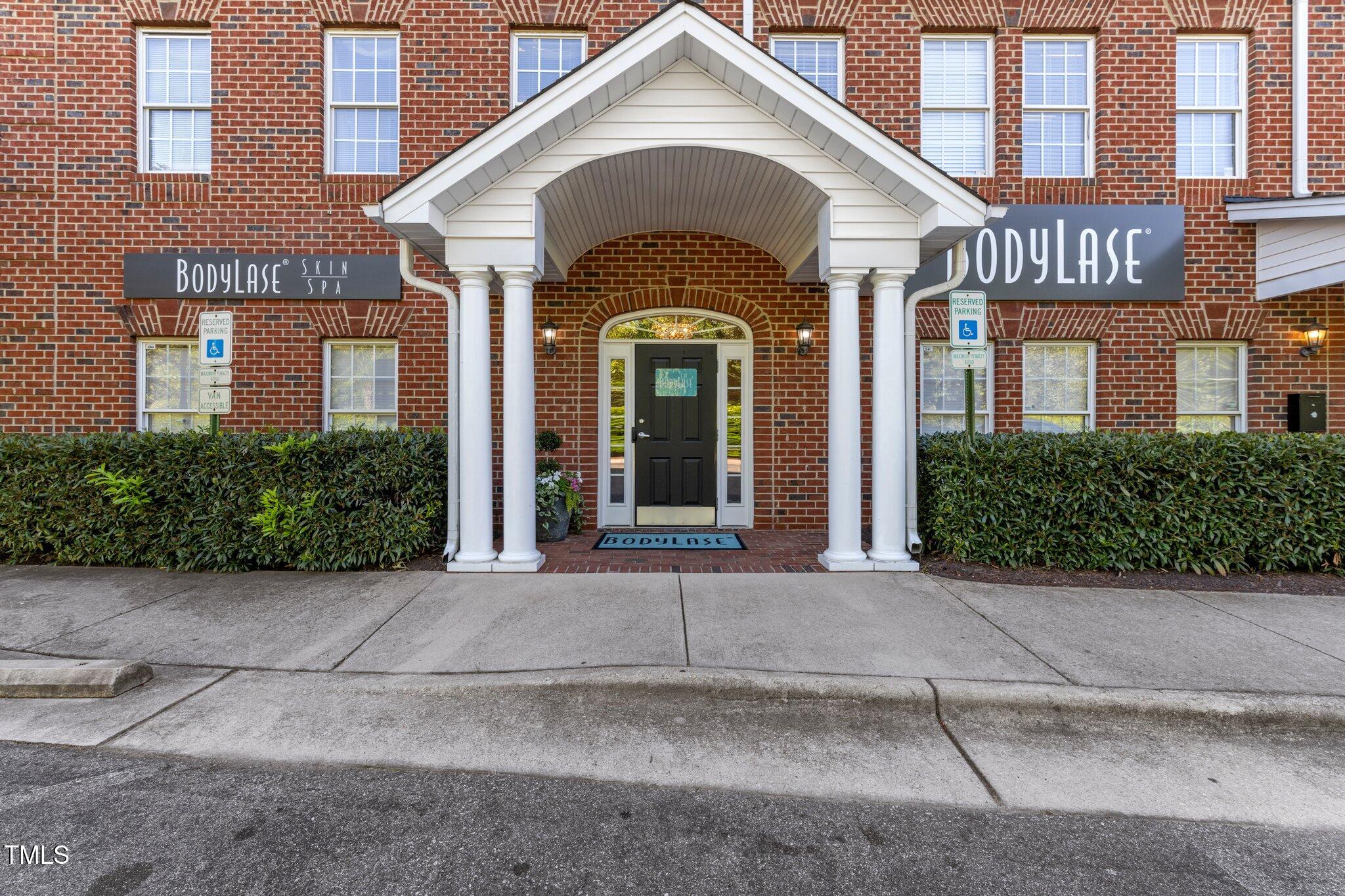 Brick commercial building entrance with a white-columned portico and BodyLase signage.