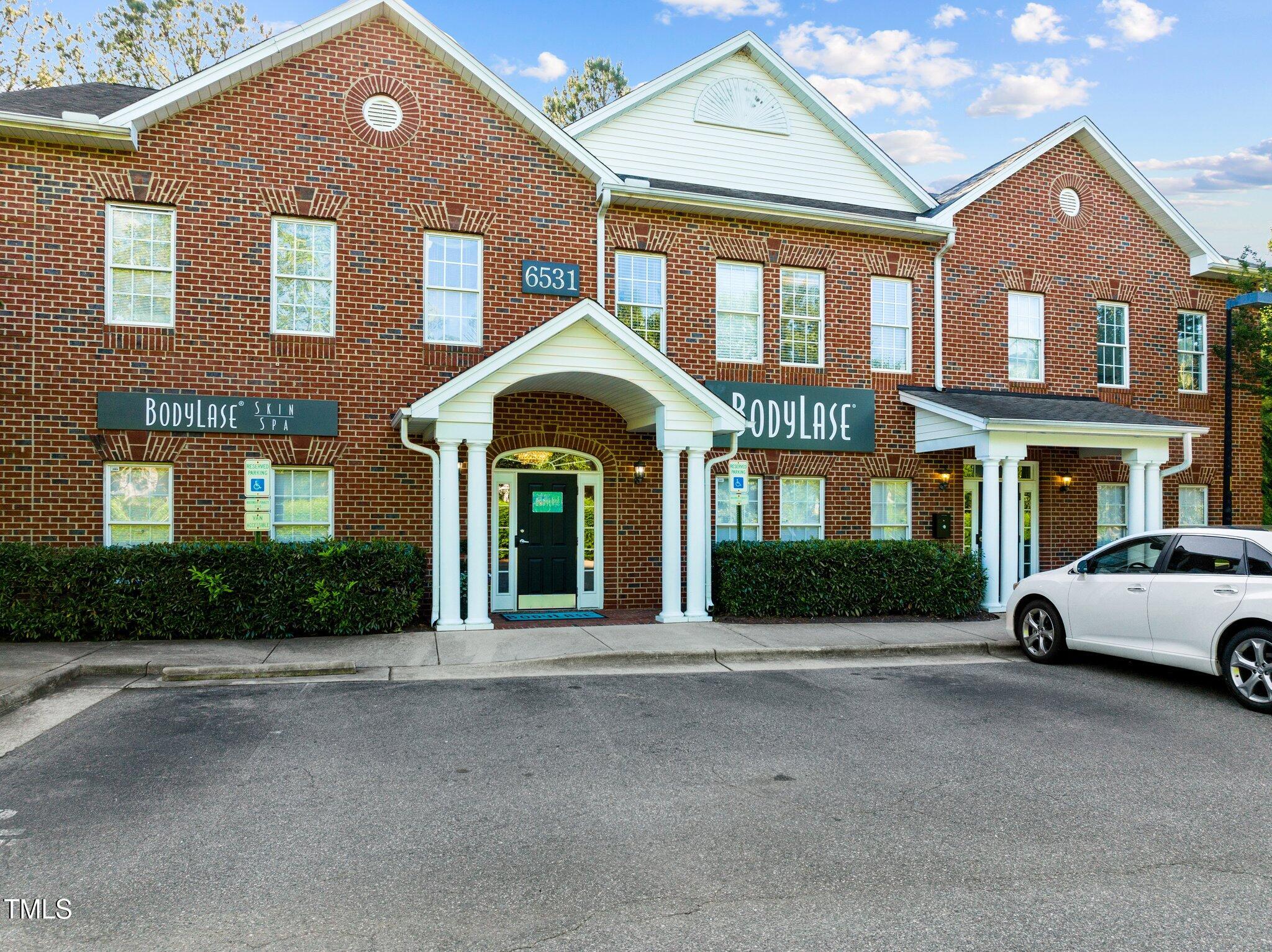 Red-brick building at 6531 Creedmoor Road with white gabled entrance canopies and BodyLase signs.
