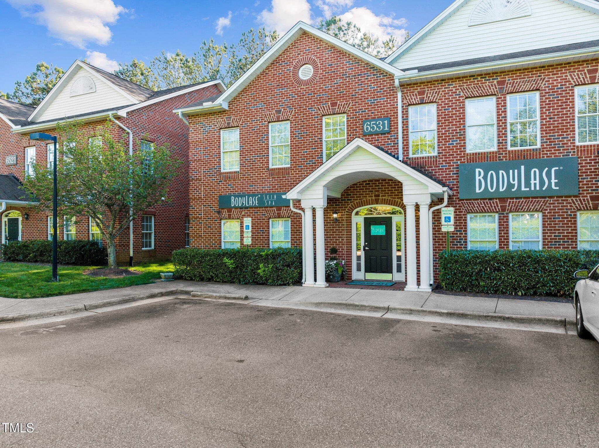 Red-brick commercial building with white gables, a covered entrance, and BodyLase signs.