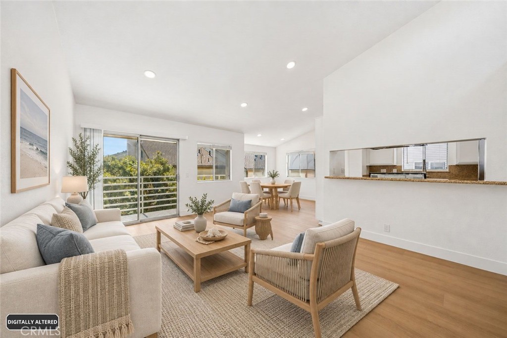 Open-plan living room with cream sofa, wood furnishings, and sliding glass doors overlooking greenery.