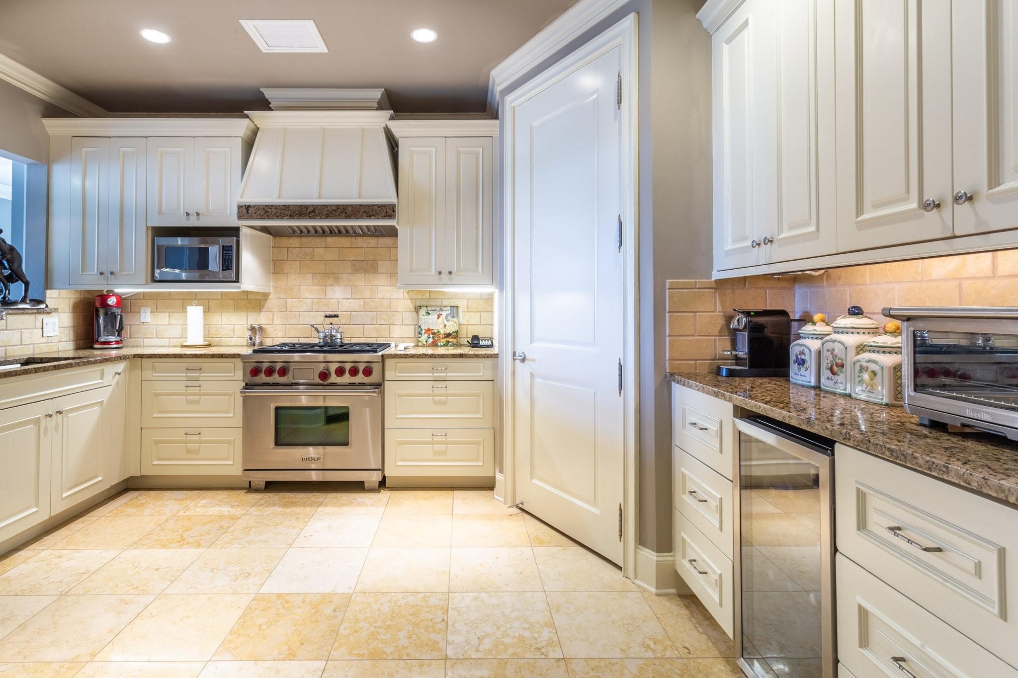 Kitchen with cream cabinets, granite counters, and a stainless Wolf range.