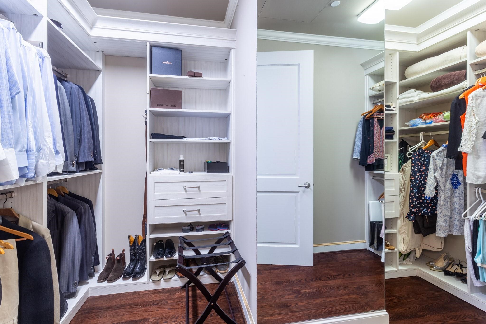 Walk-in closet with white built-in shelving, abundant clothing storage, a large mirror, and dark hardwood floors.