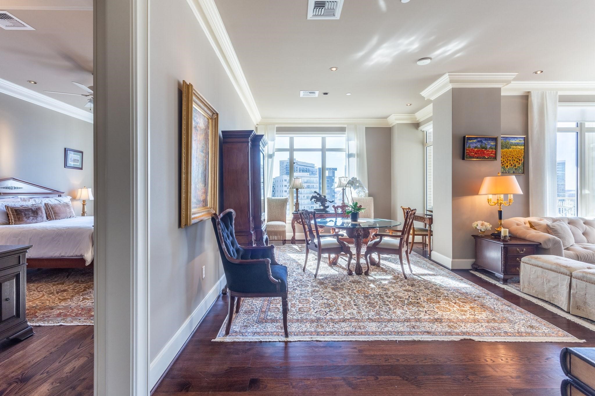 Furnished condo living and dining area with downtown views and a bedroom visible through the left doorway.