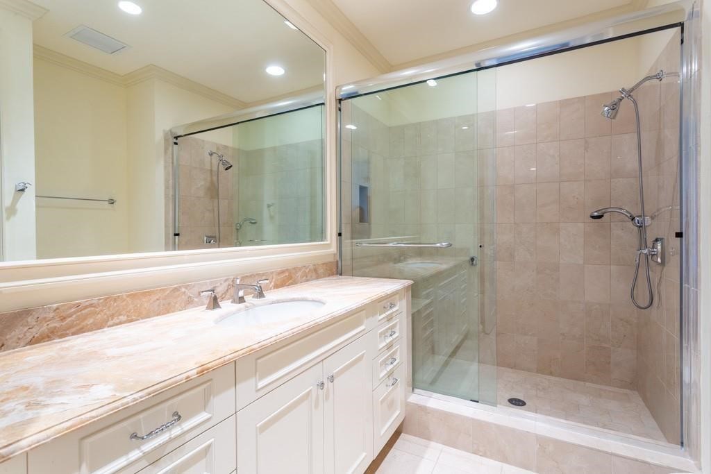 Bathroom with a marble vanity and glass-enclosed tiled shower.