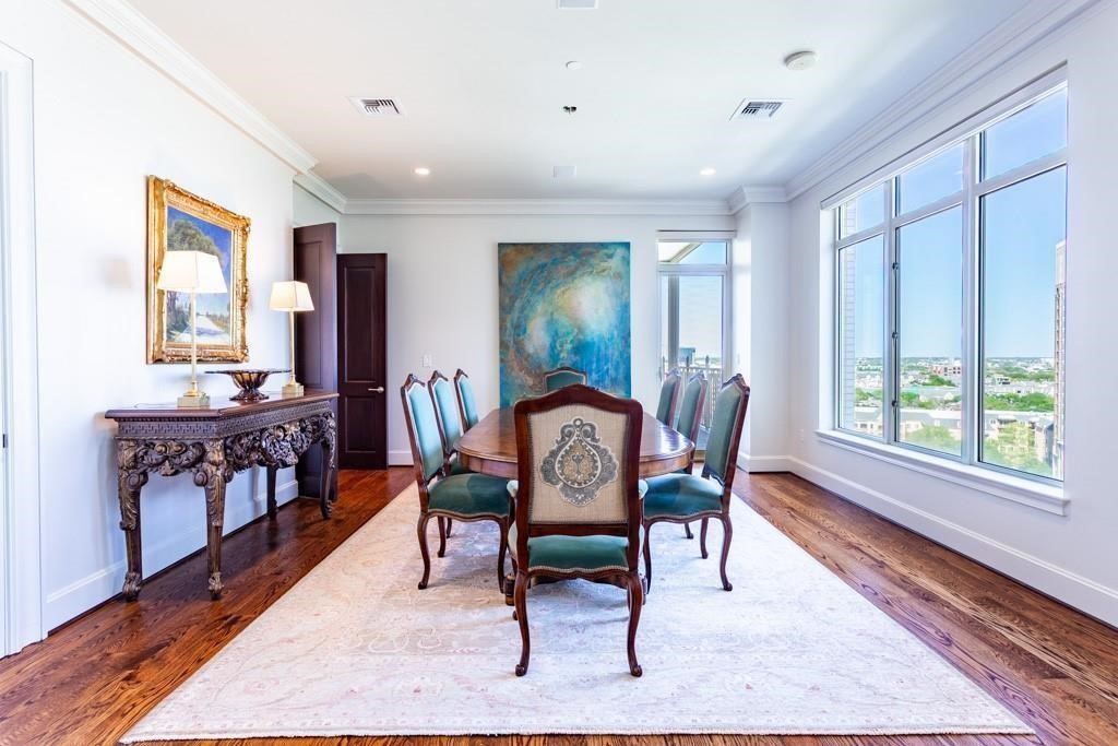 Furnished dining room with an oval table, ornate chairs, and large windows overlooking the city.