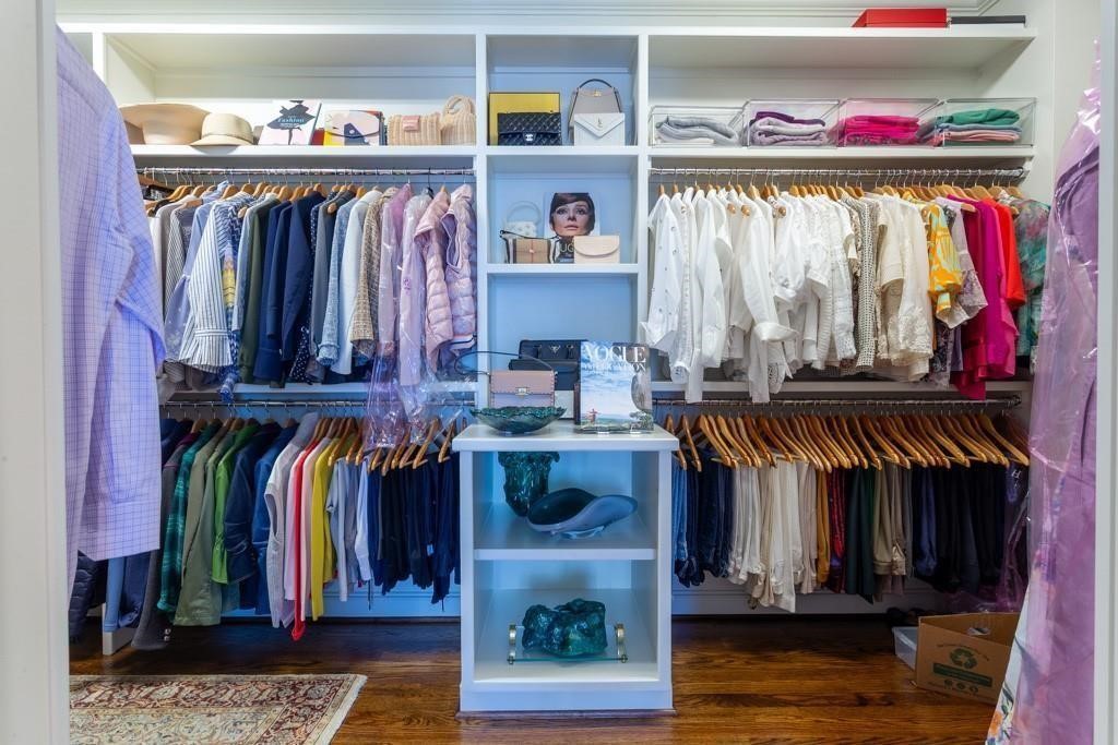 Walk-in closet with clothing racks, upper shelves, and a central display island.