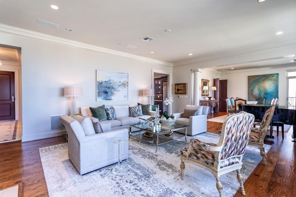 High-rise living and dining room with pale seating, hardwood floors, and abstract artwork.