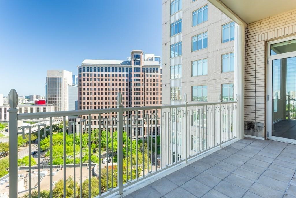 High-rise balcony overlooking downtown Dallas, with tiled flooring and a metal railing.
