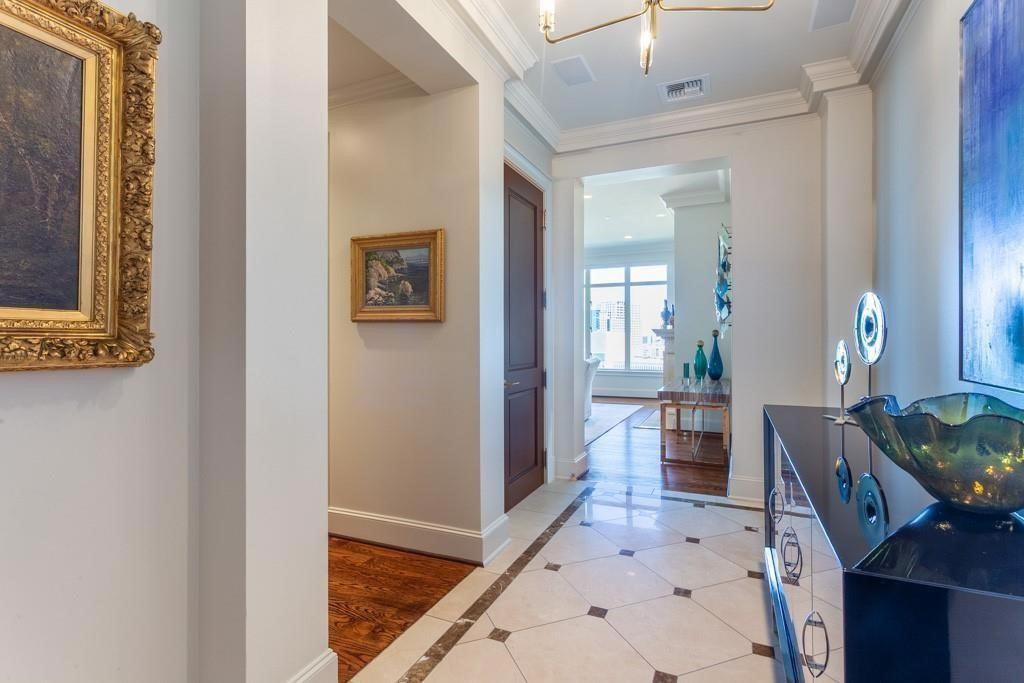 Condo entry hall with marble flooring, ornate ceiling molding, and a console decorated with blue glass accents.