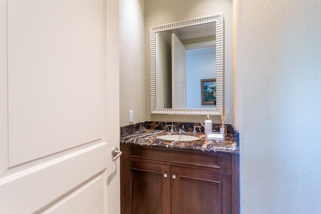 Bathroom vanity with dark wood cabinets, a veined marble countertop, and a large framed mirror.