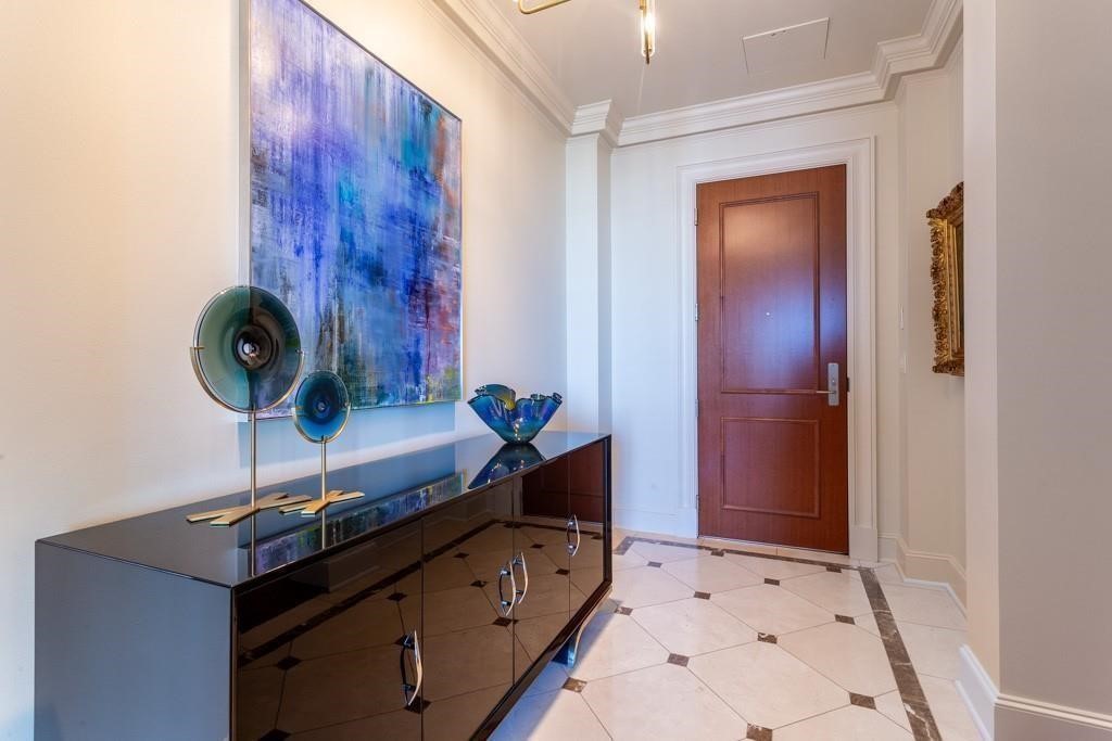 Furnished foyer with a reddish-brown door, marble tile floor, and glossy console beneath an abstract painting.