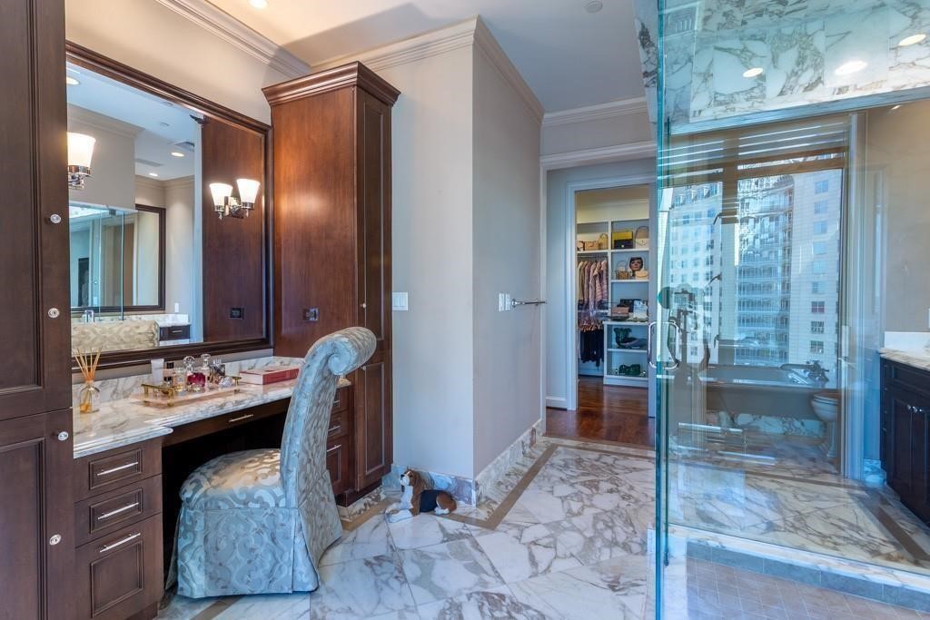 Marble bathroom with dark wood vanity, glass shower, and city buildings visible through the window.