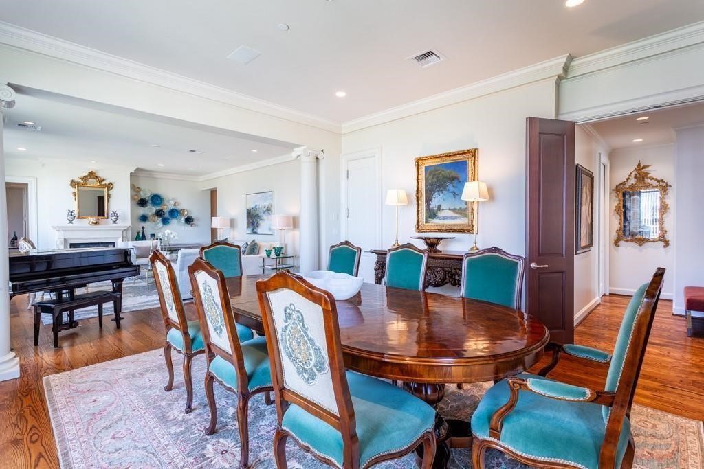 Dining room with a polished wood table, turquoise chairs, and an open view into the living room.