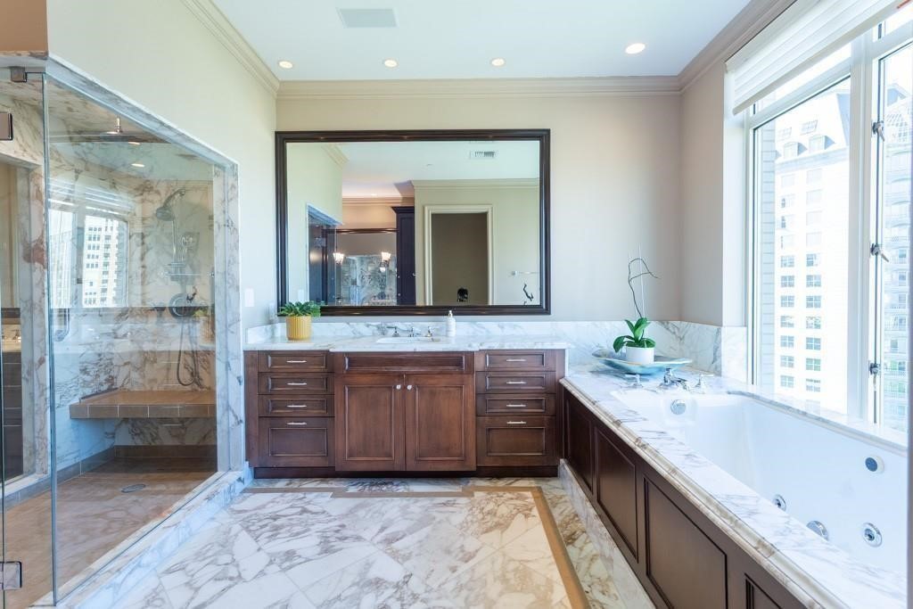 High-rise bathroom with a marble shower, dark wood vanity, jetted tub, and large windows.