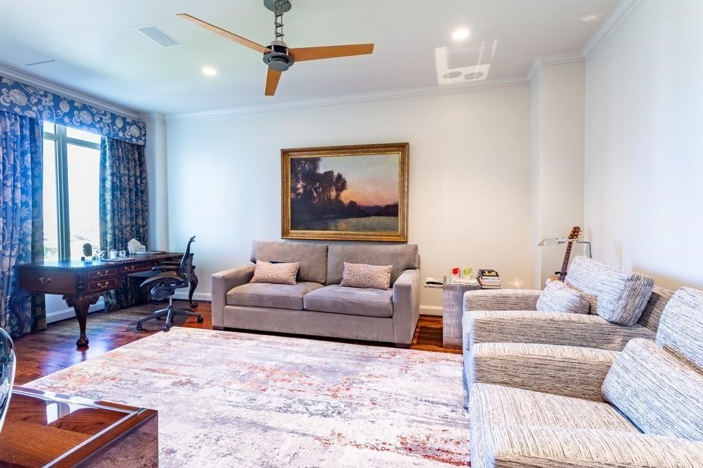 Living room with a gray sofa, patterned armchairs, and a desk by the window.