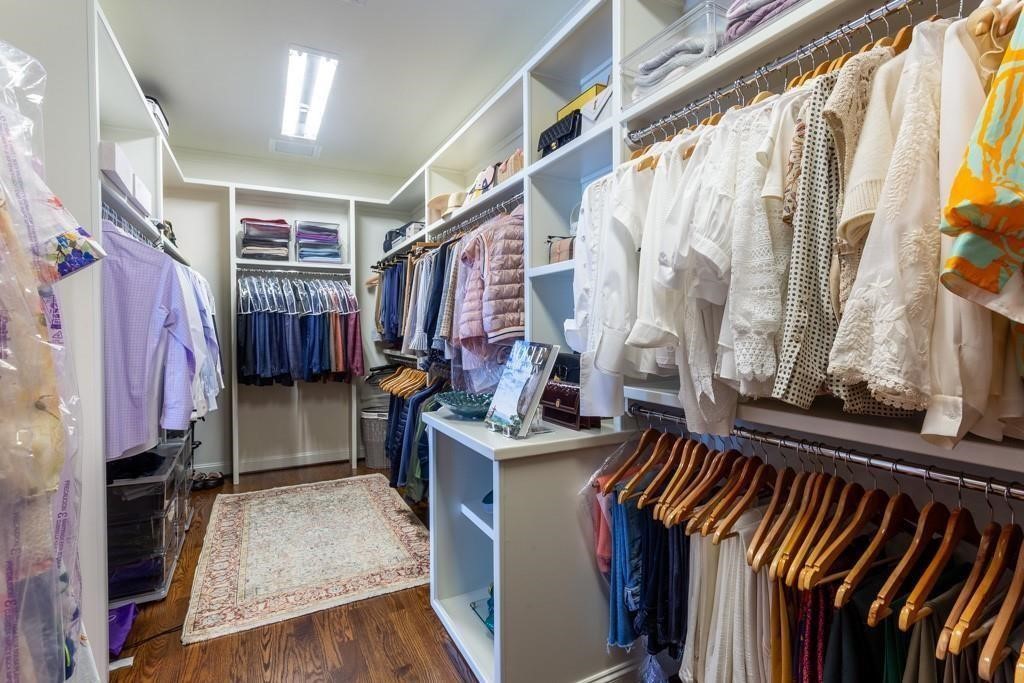 Walk-in closet with built-in shelving, clothing racks, a central island, and a patterned rug.