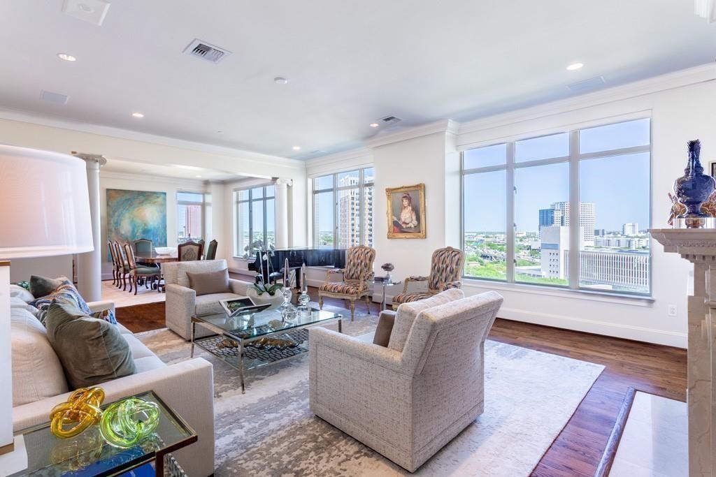 Furnished condo living room with floor-to-ceiling windows overlooking the Dallas cityscape.