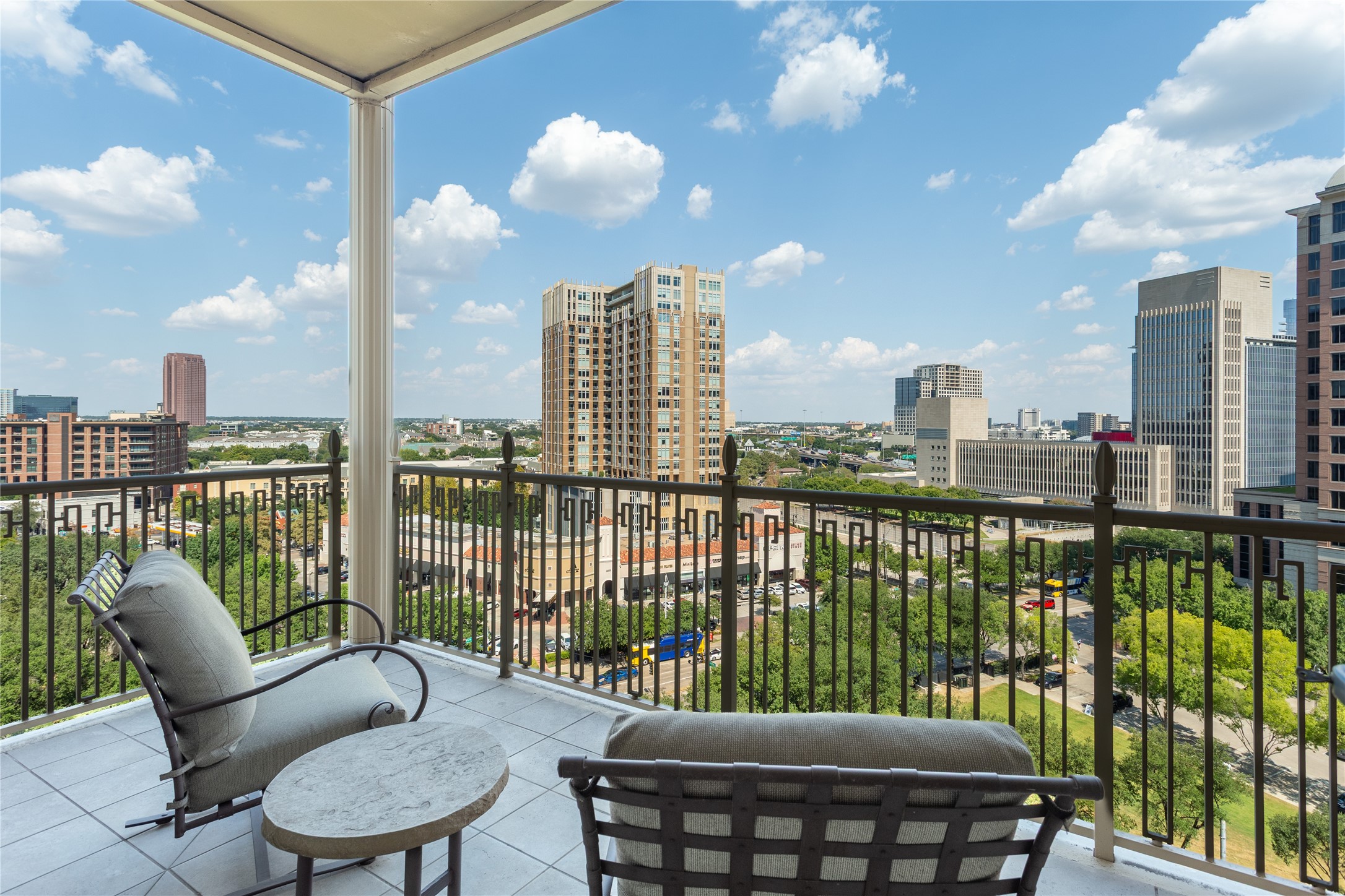 High-rise balcony with cushioned lounge chairs overlooking the Dallas skyline.