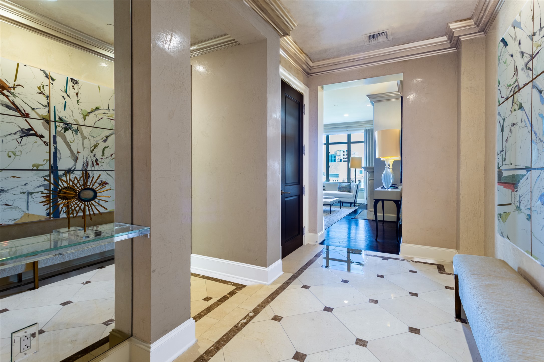 Condo entry foyer with marble floors, abstract wall art, and a view into the living room.