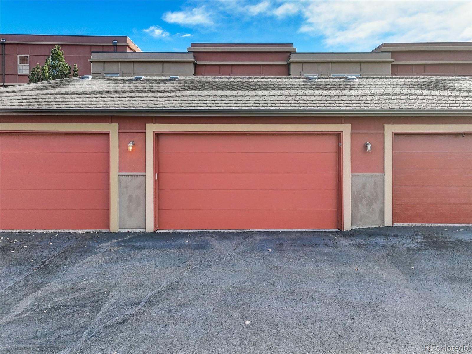 Row of red garage doors with beige trim and a paved driveway.