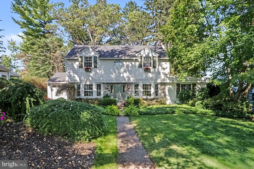 Two-story gray house with dormer windows, a landscaped front lawn, and a path to the entrance.