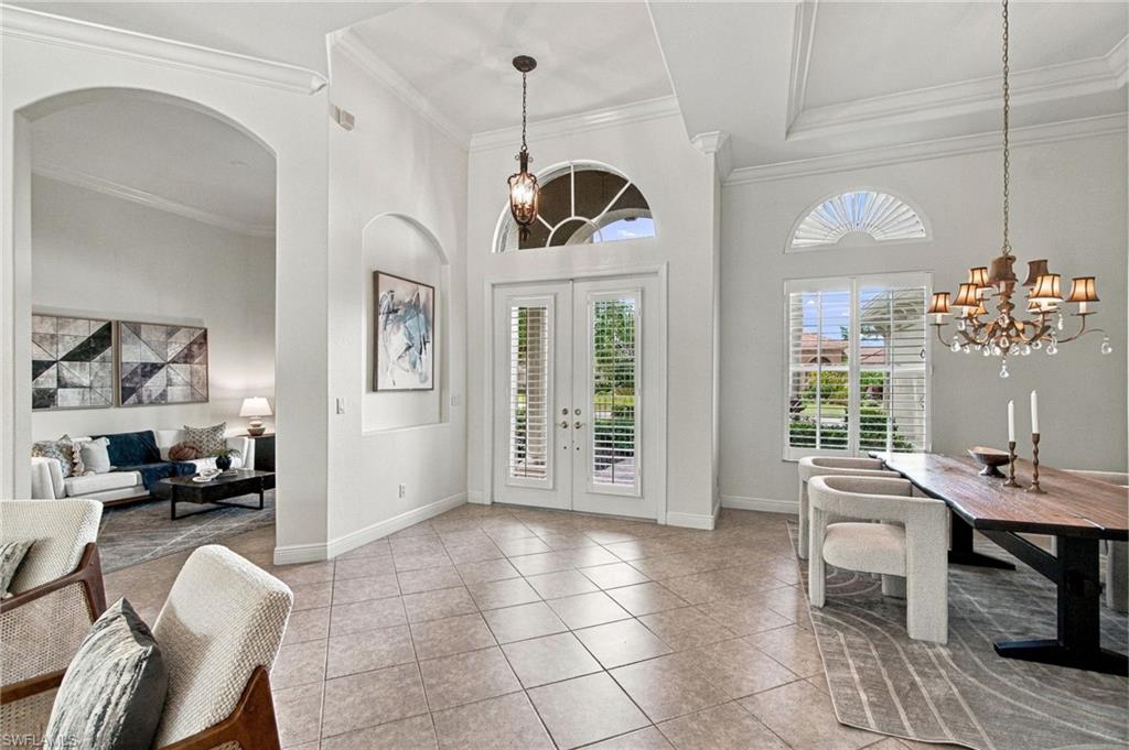 Foyer with arched transom over double doors, tiled floors, and adjoining living and dining areas.