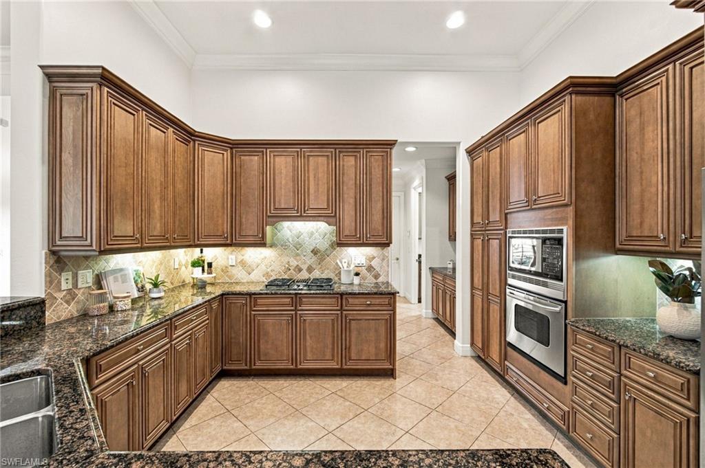 Kitchen with extensive wood cabinetry, granite counters, tiled backsplash, and double wall oven.
