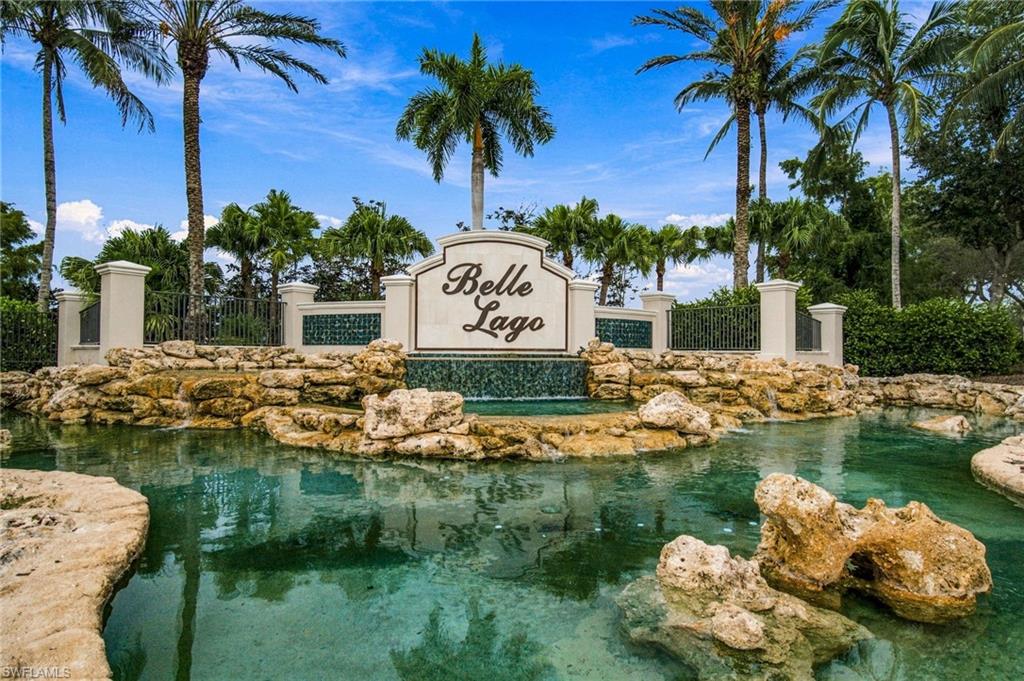 Belle Lago entrance sign above a rock-edged water feature and landscaped pond.
