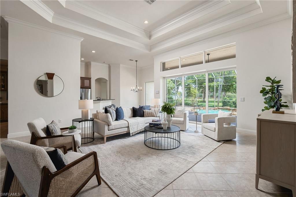 Furnished living room with a tray ceiling and sliding doors overlooking a screened pool.