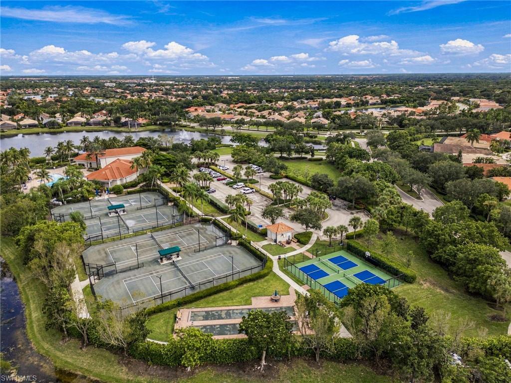 Aerial view of community tennis and pickleball courts beside a canal and landscaped homes.