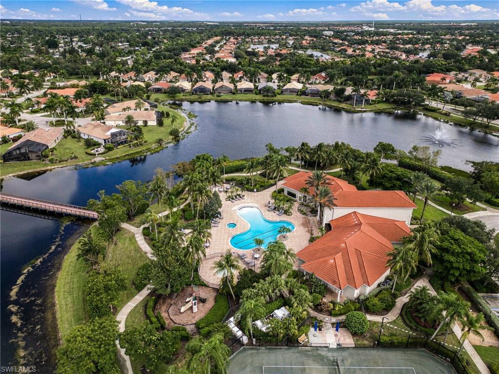 Aerial view of a lakefront community with a pool, tennis court, and homes.