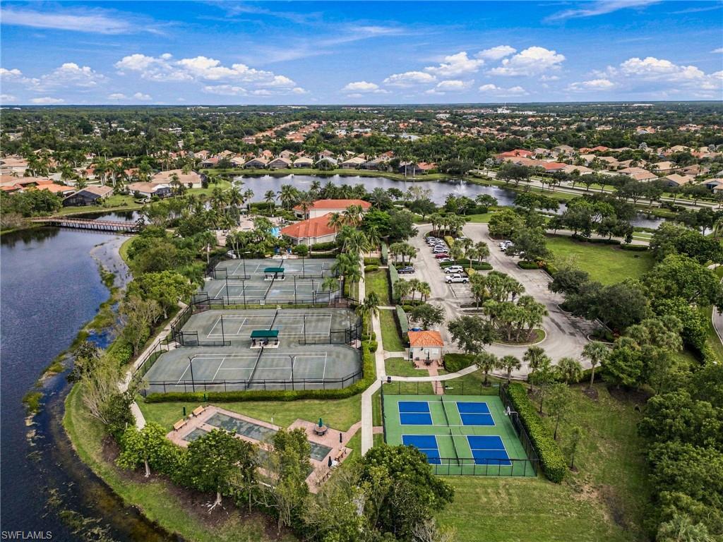 Aerial view of a community with tennis and pickleball courts beside a lake.