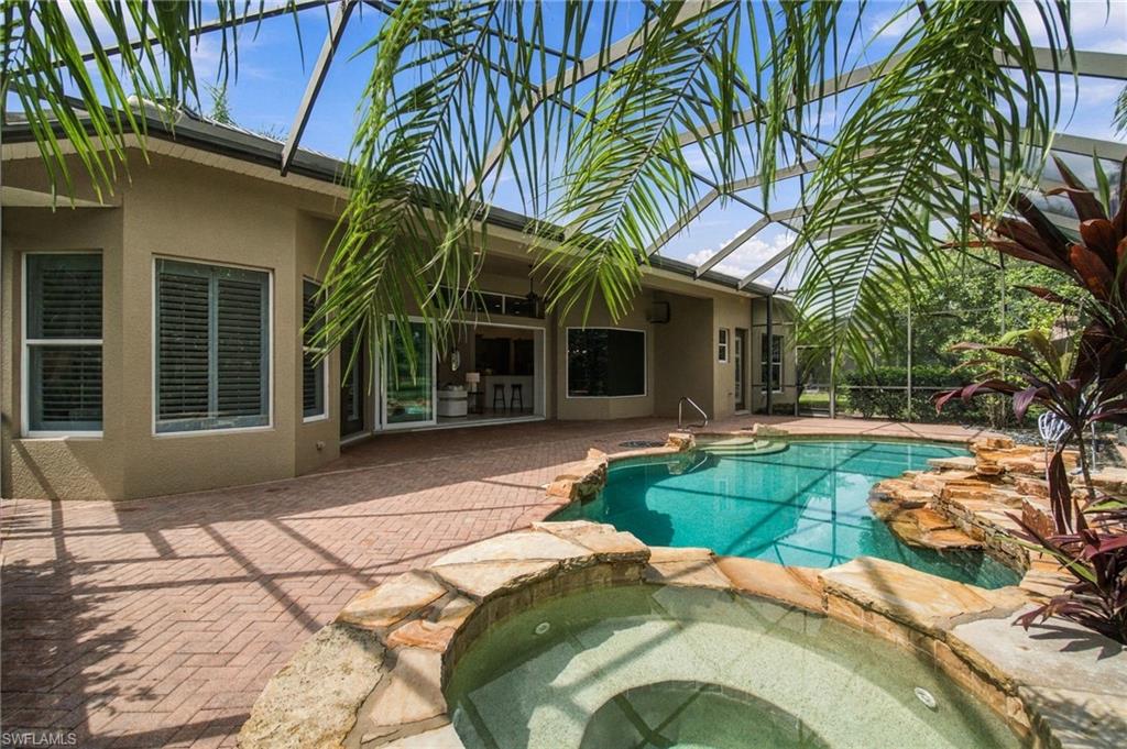 Backyard pool and raised spa beside a screened patio at a single-story home.