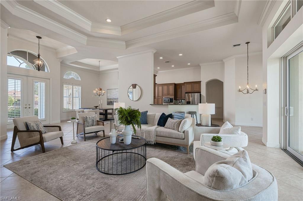 Furnished living room with tray ceiling, neutral seating, and an open view into the kitchen.