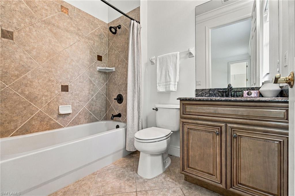 Bathroom with a tiled tub and shower, toilet, and wood-tone vanity.