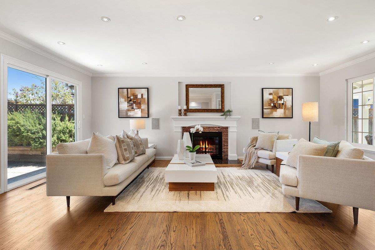 Living room with cream sofas, a lit fireplace, and sliding glass doors to the yard.