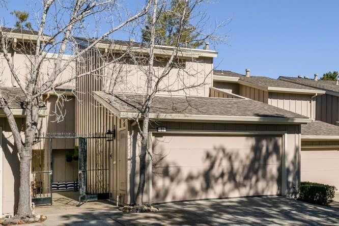 Two-story beige home with a large garage and leafless trees in front.